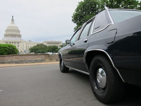 1991 Ford LTD Crown Victoria - Low side view of a dark four-door sedan parked along a street with the U.S. Capitol dome in the background.