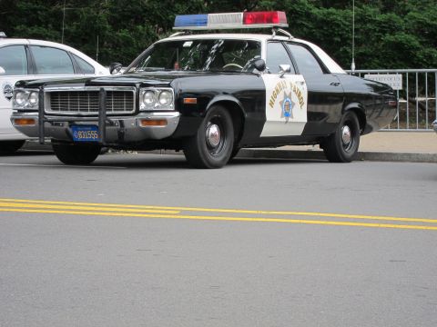 1991 Ford LTD Crown Victoria - black-and-white highway patrol cruiser with a brush guard and roof light bar viewed at an angle on a street.