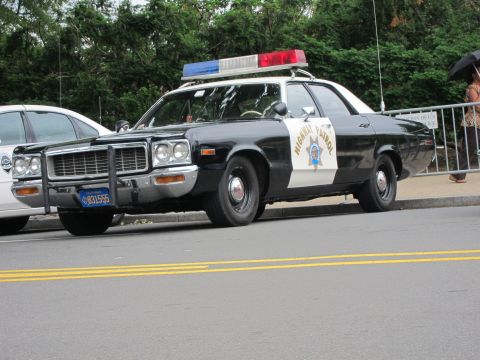 1991 Ford LTD Crown Victoria - black-and-white highway patrol cruiser with a gold star door emblem and red and blue roof lights parked curbside.