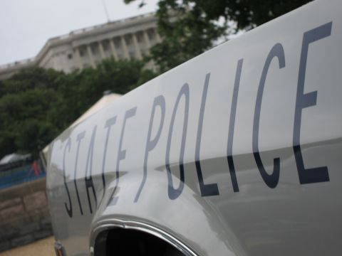 1991 Ford LTD Crown Victoria - close-up of STATE POLICE lettering on the white body panel of a car with a domed government building behind.