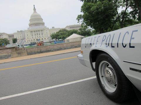 1991 Ford LTD Crown Victoria - white State Police car parked on a street with the US Capitol dome visible in the background under a gray sky.