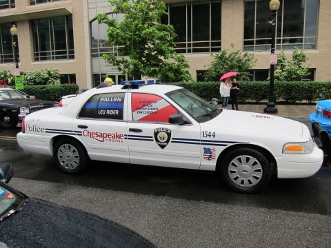 1991 Ford LTD Crown Victoria - white Chesapeake Virginia police sedan with a fallen-officer memorial window decal, side view on a wet street.