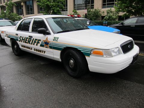1991 Ford LTD Crown Victoria - white Seminole County Sheriff sedan with green striping, a star emblem and unit number 312 parked on a street.