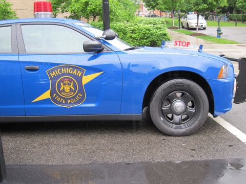 1991 Ford LTD Crown Victoria - Front-end detail of a blue Michigan State Police car showing its gold star door emblem and a hood-mounted STOP sign.