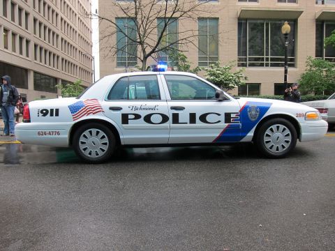 1991 Ford LTD Crown Victoria - white Richmond Police sedan numbered 289 with American flag and blue swoosh graphics parked on a wet downtown street.