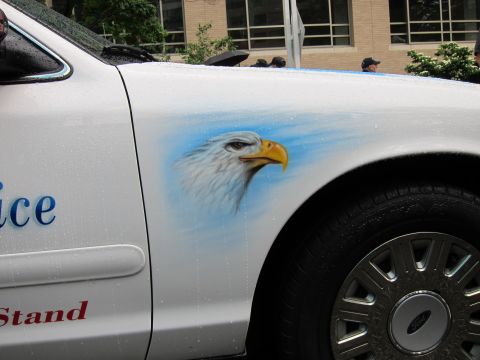 1991 Ford LTD Crown Victoria - Side of a white police car with an airbrushed bald eagle head mural near the rear wheel and partial red lettering.