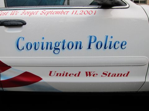 1991 Ford LTD Crown Victoria - Door of a white police car lettered Covington Police, United We Stand, with a 9/11 memorial inscription above.