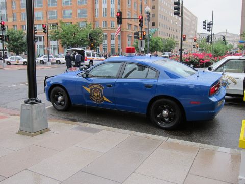 1991 Ford LTD Crown Victoria - Blue Michigan State Police Dodge Charger with a single red roof beacon parked at a curb in a downtown setting.