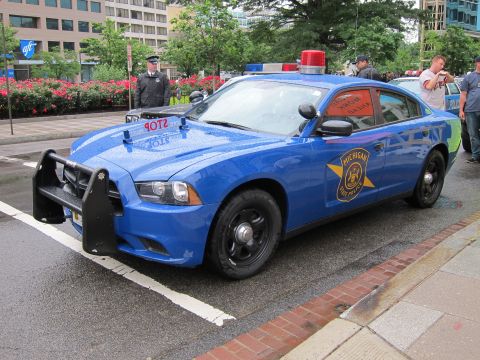 1991 Ford LTD Crown Victoria - Blue Michigan State Police Dodge Charger with a black push bumper and red roof beacon, viewed from the front quarter on a wet street.