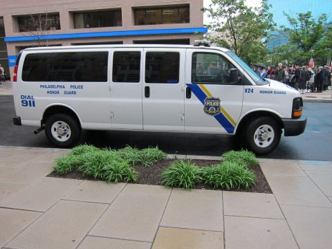 1991 Ford LTD Crown Victoria - Side view of a white Chevrolet Express van marked Philadelphia Police Honor Guard with Dial 911 lettering and a city crest.
