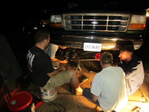 1992 Ford Bronco - Four people are gathered around the front of a 1992 Ford Bronco, working on its steering components.