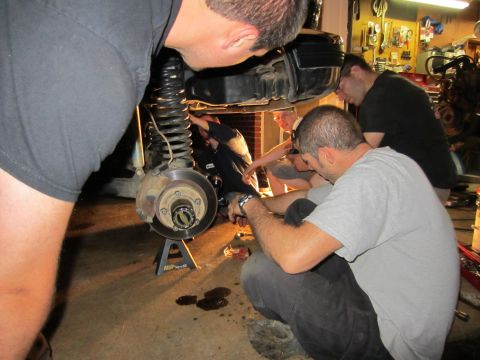 1992 Ford Bronco - A group of mechanics are working on the suspension system of a vehicle in a garage setting.