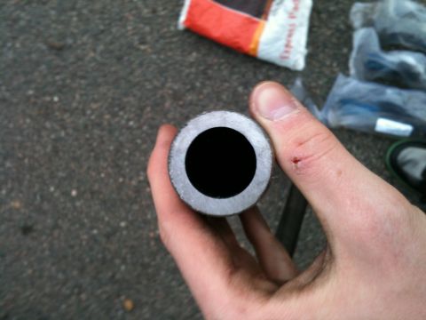 1992 Ford Bronco - A metal tube is held up to the camera, revealing its hollow interior. Other parts and packaging are visible in the background.