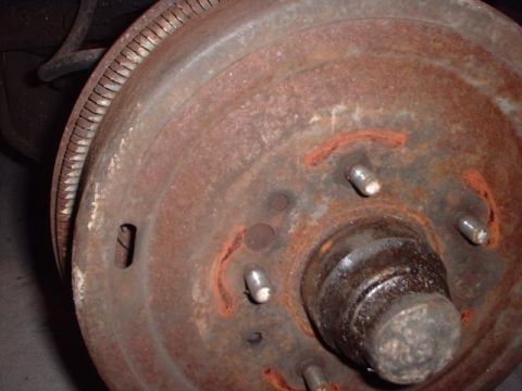 1996 Ford Taurus - This is a close-up view of a heavily rusted brake drum, showing the wheel studs and part of the suspension.