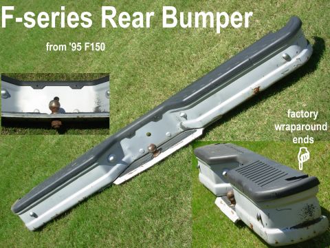 Gray Ford F-series rear step bumper with hitch ball lying on grass, with text labels.