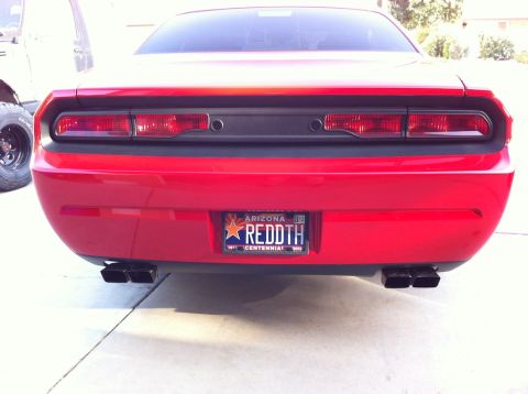 2010 Dodge Challenger - Rear view of a red 2010 Dodge Challenger, its distinctive taillights and dual exhaust pipes.