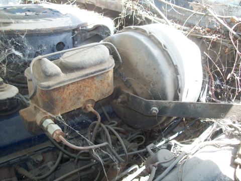 1965 Ford 427 - Close-up of a brake booster and master cylinder assembly, heavily weathered and covered in cobwebs.