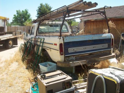 1965 Ford 427 - This Ford pickup truck, likely from the mid-1970s, is equipped with a ladder rack and appears to be in a yard with other items.