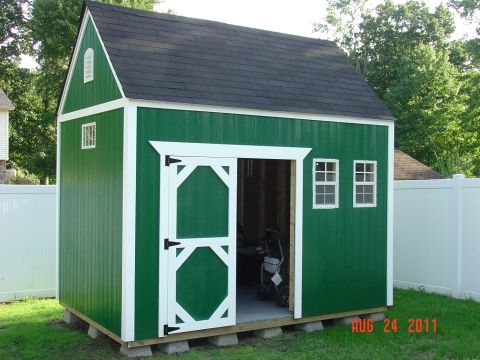 2000 Ford Crown Victoria - A green storage shed with white trim and a white fence in the background. A lawn mower is visible inside.