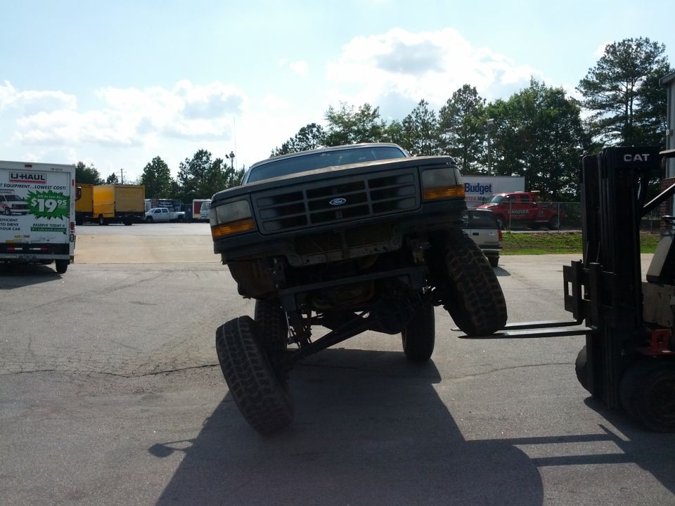 Front view of a lifted 1987 Ford Bronco being moved by a forklift