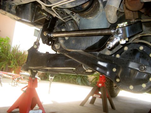 1996 Ford Bronco - Close-up of a vehicle's steering linkage and rear axle assembly, supported by jack stands.