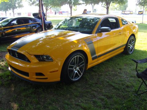2007 Ford Mustang - Yellow 2012 Ford Mustang Boss 302 with black racing stripes is parked on grass next to another car.