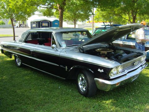 2007 Ford Mustang - A classic two-tone Ford Galaxie 500 is displayed with its hood up, parked on a grassy area next to another vehicle.