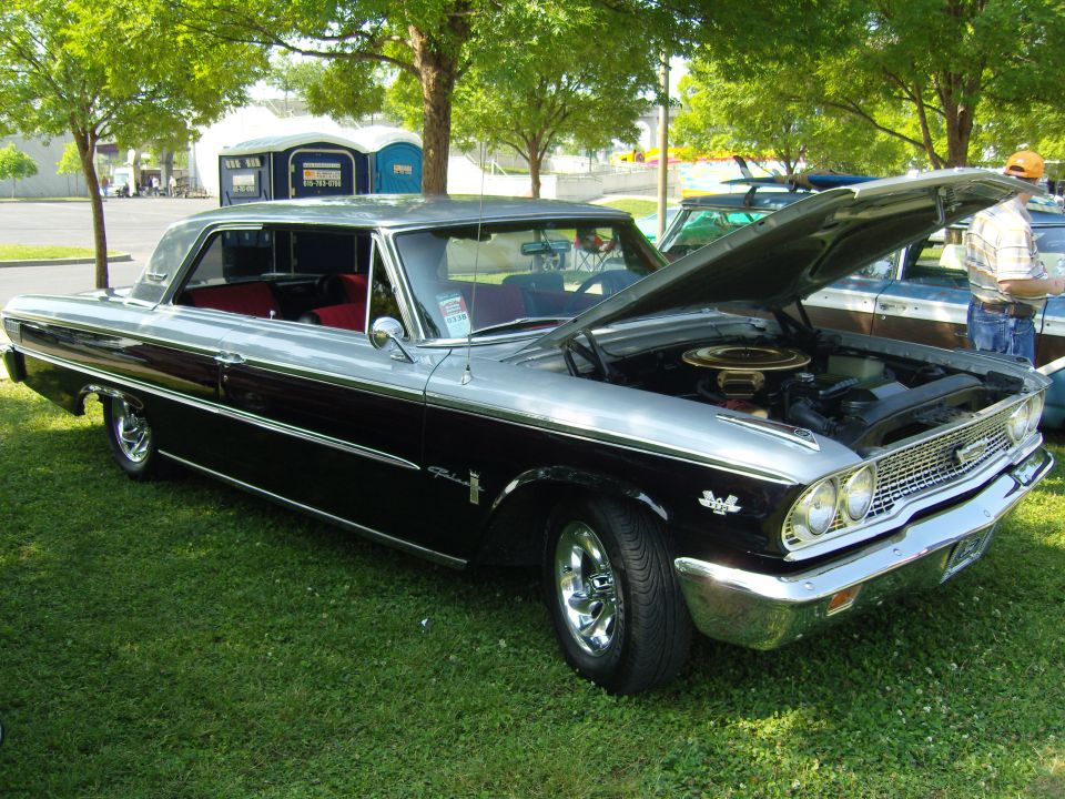 Two-tone black and silver 1963 Ford Galaxie 500 with hood open, parked on grass