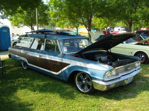 2007 Ford Mustang - A vintage blue station wagon with wood paneling and surfboards on its roof rack is displayed with its hood open.