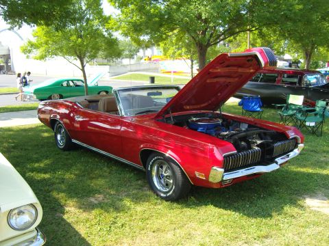 2007 Ford Mustang - A red 1969 Mercury Cougar convertible is displayed with its hood open at an outdoor car show.