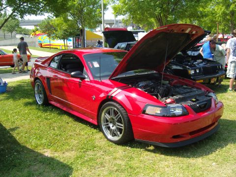 2007 Ford Mustang - A red 2007 Ford Mustang is displayed with its hood open at an outdoor event.