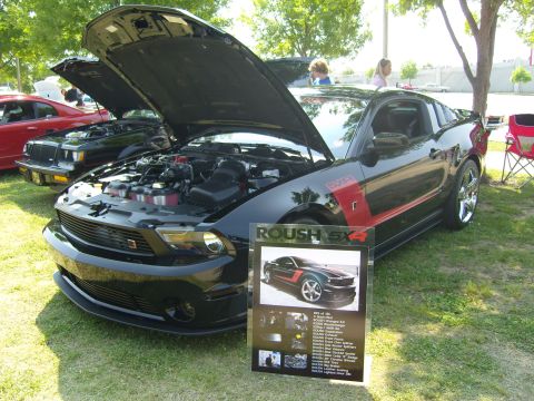 2007 Ford Mustang - A black 2007 Ford Mustang Roush SX4 is displayed with its hood open, alongside a descriptive sign.