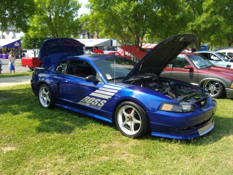 2007 Ford Mustang - A blue Mustang with custom decals is displayed with its hood and trunk open at an outdoor event.