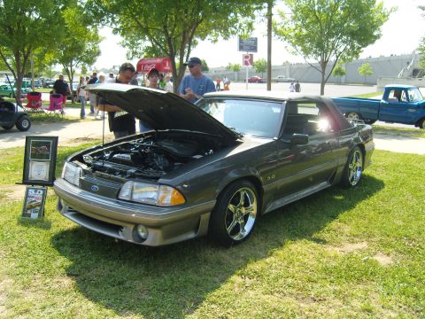 2007 Ford Mustang - A dark gray 1990 Ford Mustang convertible is displayed with its hood open at an outdoor event, with other vehicles and people in the backgr…