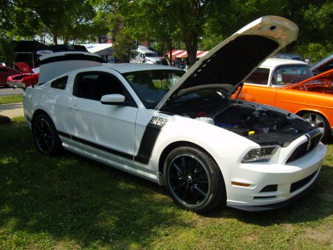 2007 Ford Mustang - A white 2012 Ford Mustang Boss 302 is displayed with its hood open, revealing the engine and distinctive black racing stripes on the side.