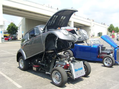 2007 Ford Mustang - A heavily modified Volkswagen Beetle is displayed with its engine exposed, alongside a blue hot rod with its hood open.
