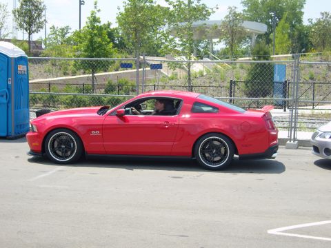 2007 Ford Mustang - Red coupe with custom wheels and a 5.0 badge is seen from the side.