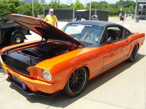 2007 Ford Mustang - This custom 1965 Ford Mustang coupe features a striking orange and black paint scheme with the hood raised to display its engine.