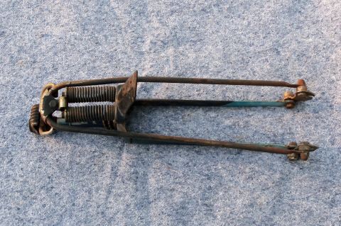 1994 Ford Bronco - A close-up view of a rusty, old car part with visible springs and fasteners against a textured background.