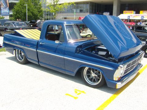 2007 Ford Mustang - Custom blue pickup truck with a wood-slatted bed and lowered suspension is displayed with its hood open.