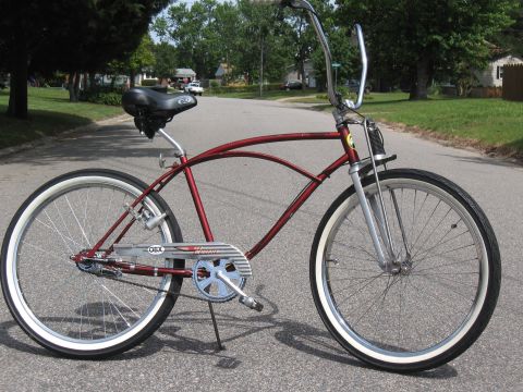 1994 Ford Bronco - A classic red cruiser bicycle with whitewall tires is parked on a suburban street.