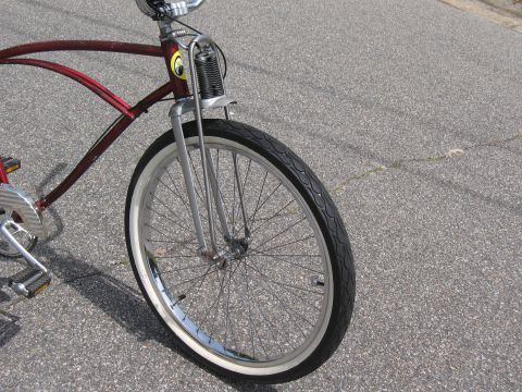 1994 Ford Bronco - A custom cruiser bicycle with a metallic red frame and chrome accents is parked on asphalt.