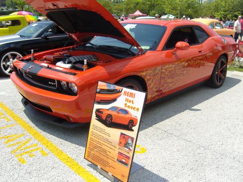 2007 Ford Mustang - A 2011 Dodge Challenger SRT with custom flame graphics is displayed with its hood open at a car show.