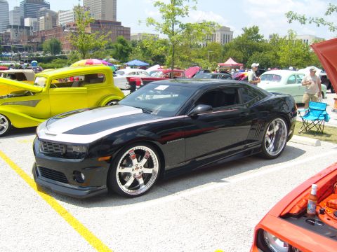 2007 Ford Mustang - A black and silver coupe with custom chrome wheels is parked at an outdoor car show.