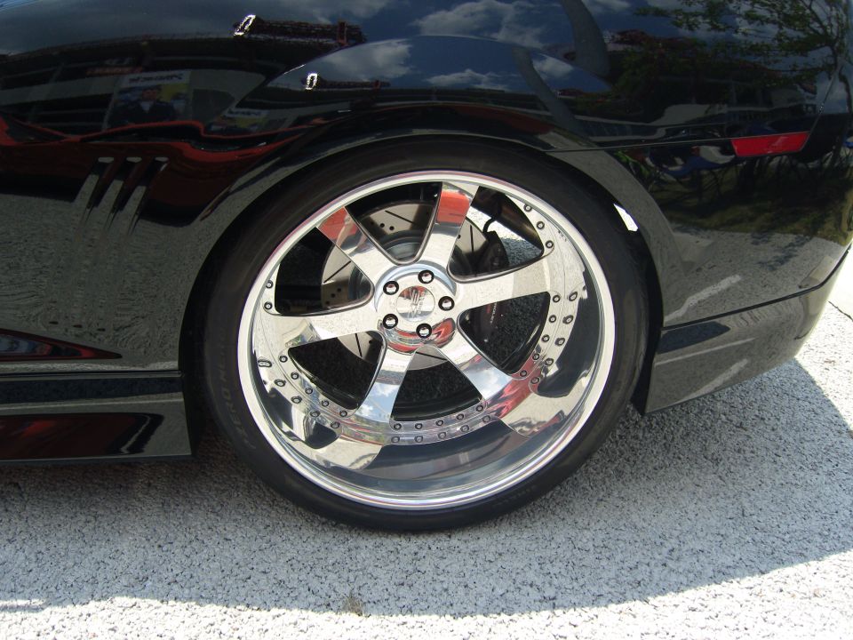 Close-up of a shiny chrome five-spoke wheel with drilled rotors on a black car