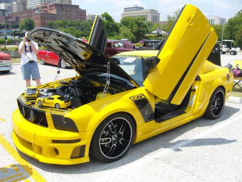 2007 Ford Mustang - A bright yellow custom Ford Mustang is displayed with its hood and doors open, revealing the engine and interior.