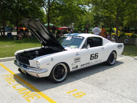 2007 Ford Mustang - A classic white 1965 Ford Mustang Fastback with racing decals and blue stripes is displayed with its hood open.