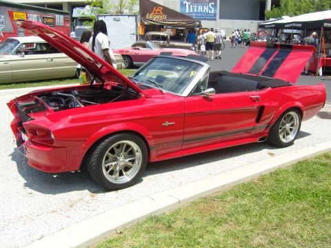 2007 Ford Mustang - A classic red convertible with racing stripes is displayed with its hood and trunk open at an outdoor event.