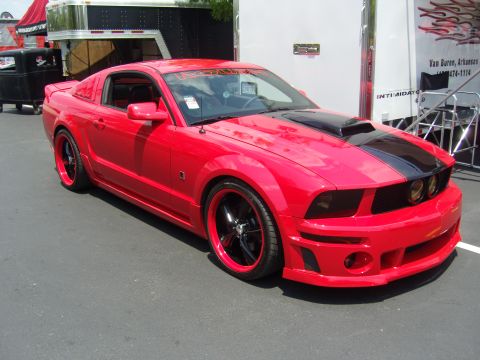 2007 Ford Mustang - A modified red Ford Mustang is parked outdoors, possibly at a car show.