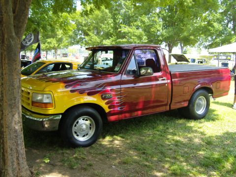 2007 Ford Mustang - A customized Ford F-150 pickup truck with a two-tone paint job flames is seen at an outdoor event.